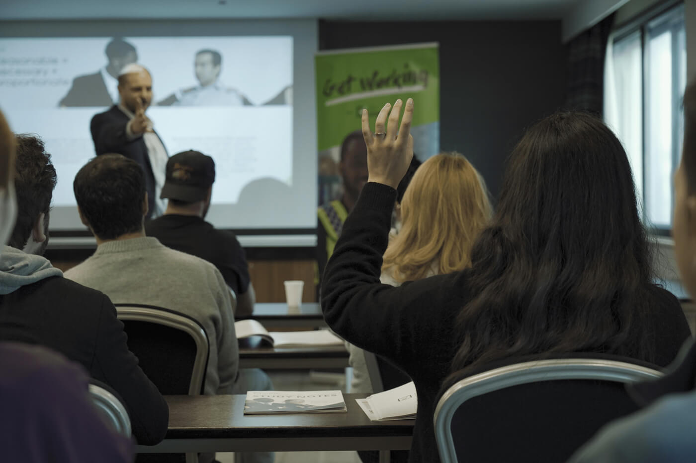 A photograph from a Get Licensed training course, showing an instructor speaking to a class of security professionals, highlighting the importance of professional training